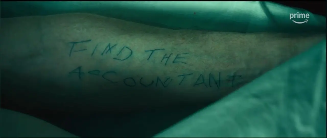 The Accountant 2 Movie Still - Ray Kings Arm with "FIND THE ACCOUNTANT" scrawled on it.