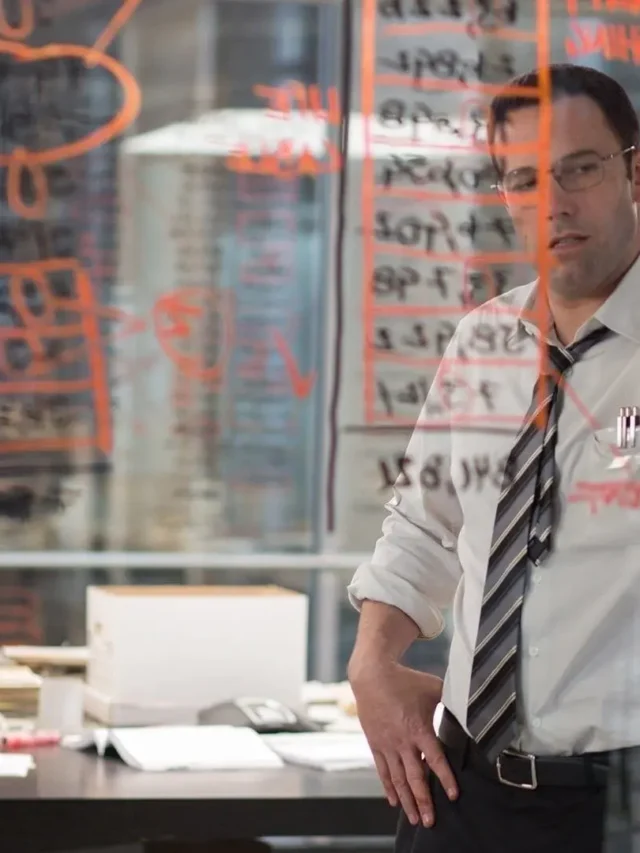 Movie still from The Accountant (2016). Christian Wolff (Ben Affleck) and Dana Cummings (Anna Kendrick) intensely focused on papers, working on the Living Robotics audit in The Accountant.